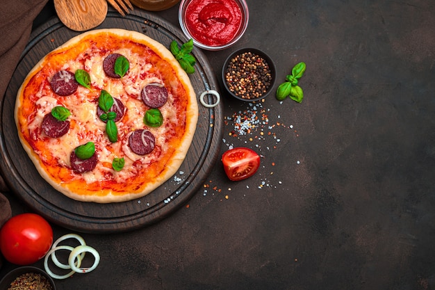 Pizza fraîche et délicieuse et ingrédients sur fond marron. Vue de dessus avec espace de copie. Le concept d'arrière-plans culinaires.