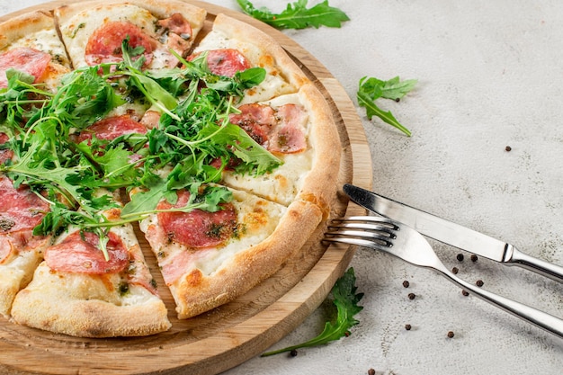 Pizza fraîche avec de la viande et du jambon sur le fond de béton