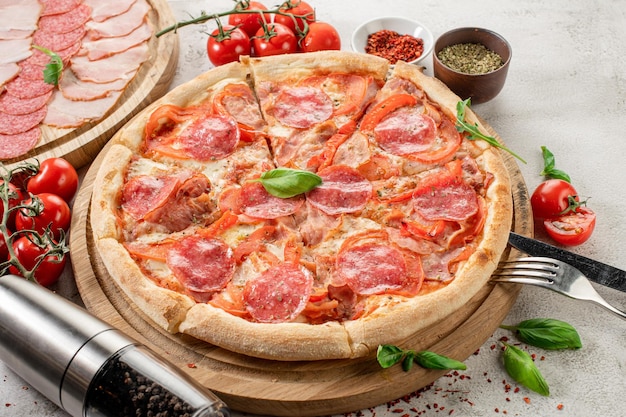 Pizza fraîche avec de la viande et du jambon sur le fond de béton