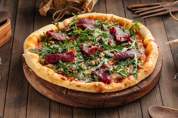 Pizza gourmande appétissante avec viande de cheval séchée et roquette