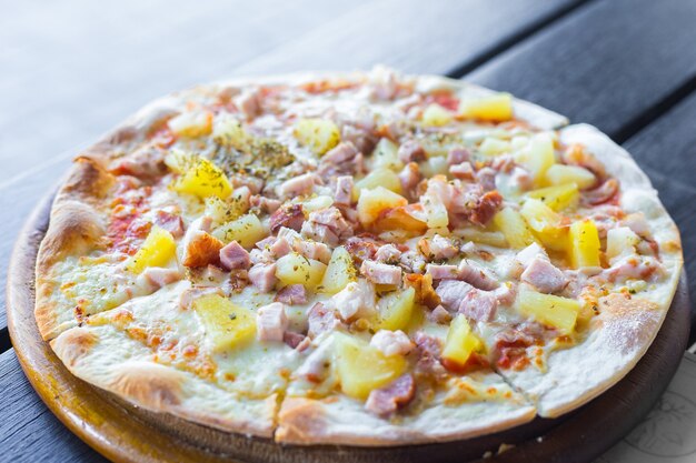 La pizza hawaïenne est un plat italien qu'elle prépare avec de la sauce tomate, de l'ananas haché, du jambon et du fromage.