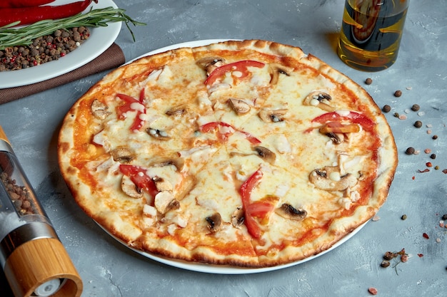 Pizza italienne au bacon, champignons, tomates, fromage fondu sur fond gris