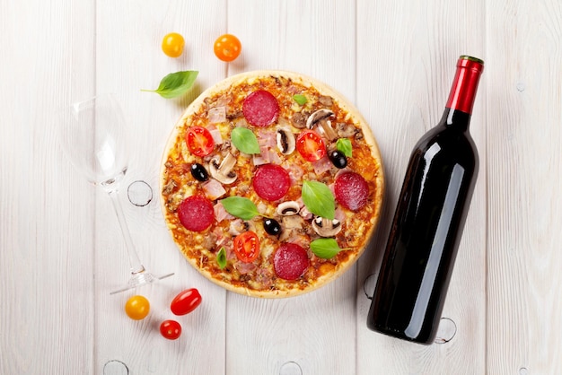 Pizza italienne au pepperoni tomates olives basilic et vin rouge