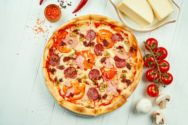 Pizza italienne au salami, jambon et olives dans une composition avec des ingrédients