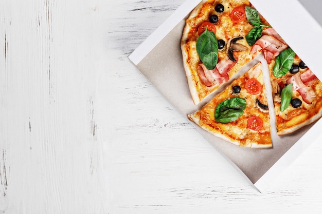 Pizza italienne aux champignons, basilic, tomate, olives et fromage sur la boîte de livraison