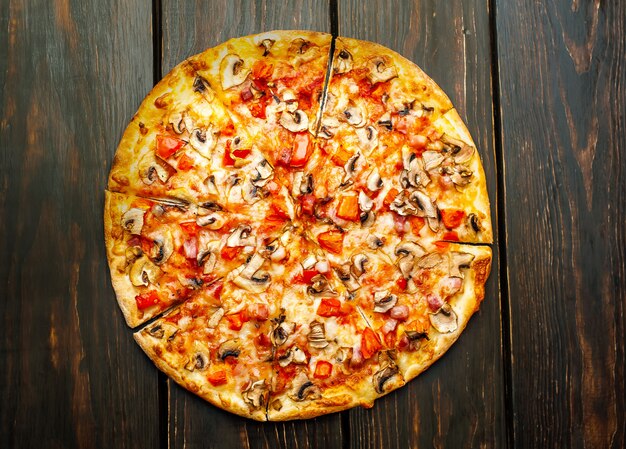 pizza italienne aux champignons, tomates et fromage sur bois