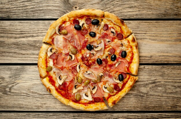 pizza italienne avec bacon, champignons, olives, tomates sur fond de bois avec copie espace pour votre texte