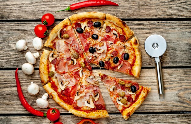 pizza italienne avec bacon, champignons, olives, tomates sur fond de bois