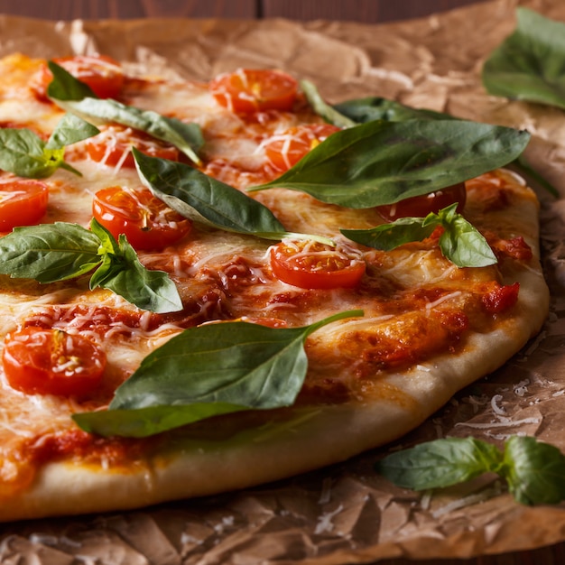 Pizza italienne faite maison avec mozzarella, tomates et feuilles de basilic.