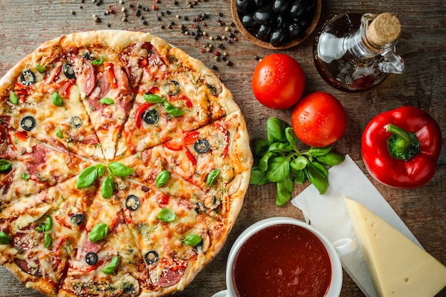 Pizza italienne et ingrédients sur une table en bois