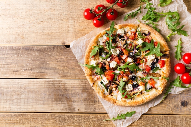 Pizza italienne de légumes aux tomates sur fond de wodeen, espace copie, vue du dessus