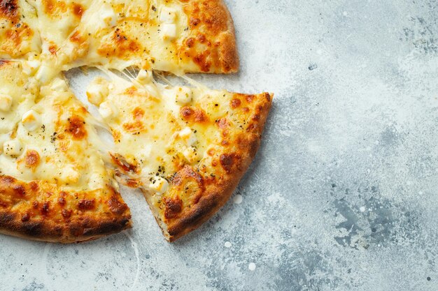 Photo pizza italienne à quatre fromages avec fromage étirable et basilic sur un fond en béton clair