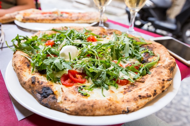 Pizza italienne à la roquette, tomate et fromage sur la table dans un restaurant à l'extérieur