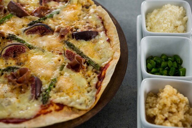 Pizza italienne servie avec des ingrédients sur un plateau à pizza