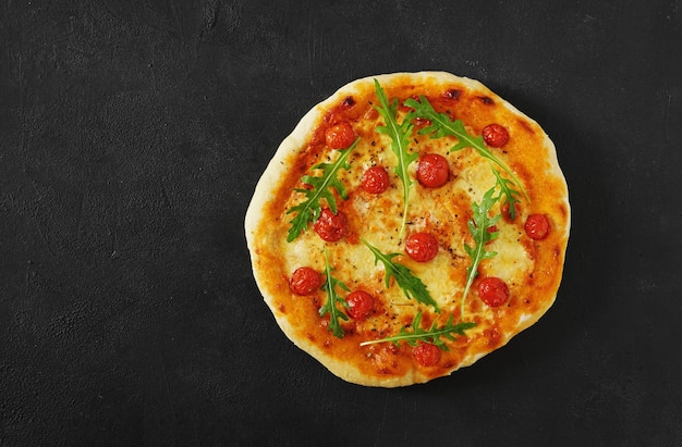 Pizza italienne traditionnelle avec tomates et rugula sur fond sombre vue de dessus maison