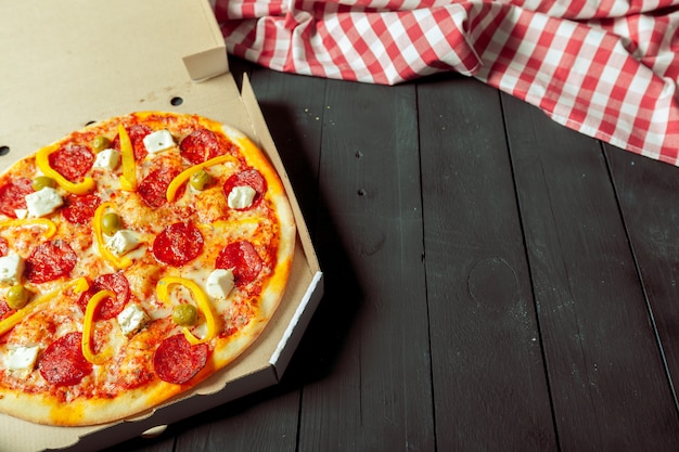 Pizza livrée dans son carton sur la table à côté du tissu