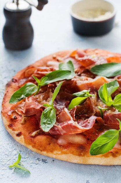 Pizza maison au jambon, mozzarella et feuilles de basilic frais