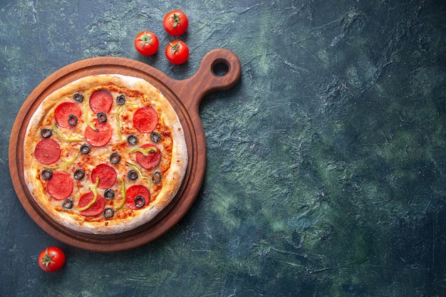 Pizza maison sur planche à découper en bois et tomates sur une surface sombre isolée