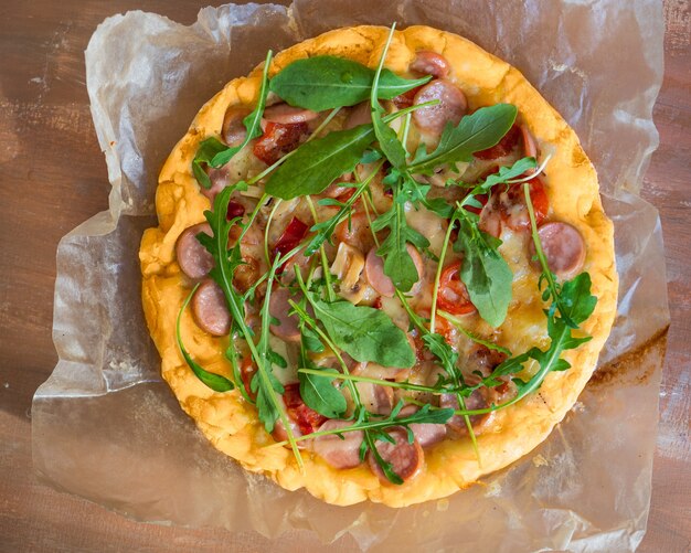 Pizza maison avec tomates saucisses et champignons en coupe et roquette toute saison Vue d'en haut