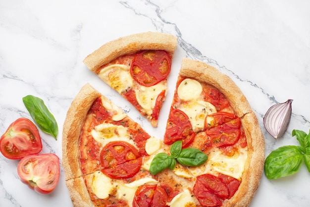 pizza margherita aux tomates et basilic sur une table en marbre blanc