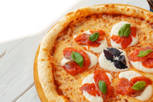 Pizza margherita chaude sur table en bois blanc