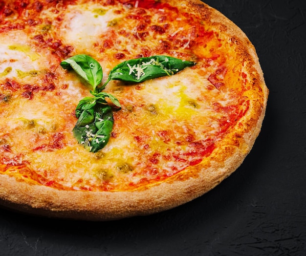 La pizza Margherita avec du basilic sur pierre noire