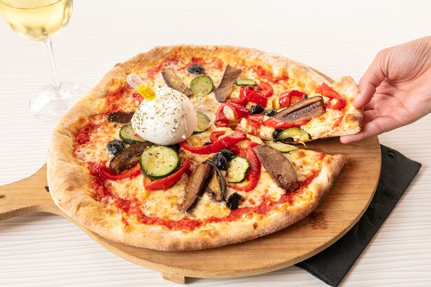 Pizza à la mozzarella et aux légumes servie sur une planche