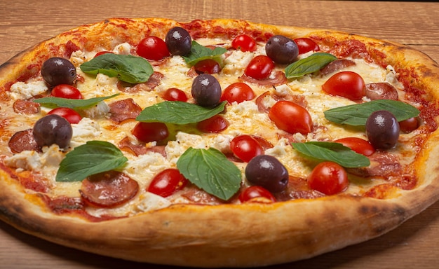 Pizza à la mozzarella de bufflonne avec tranches de tomates cerises pepperoni, olives noires et basilic