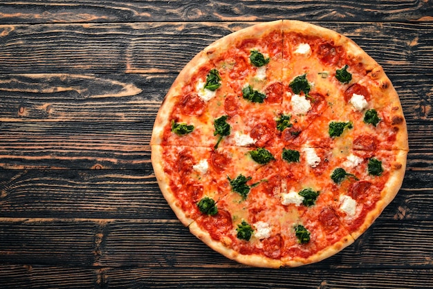 Pizza napolitaine Salami de saucisse au fromage gorgonzola aux épinards Sur un fond en bois Vue de dessus