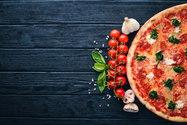 Pizza napolitaine Salami de saucisse au fromage gorgonzola aux épinards Sur un fond en bois Vue de dessus