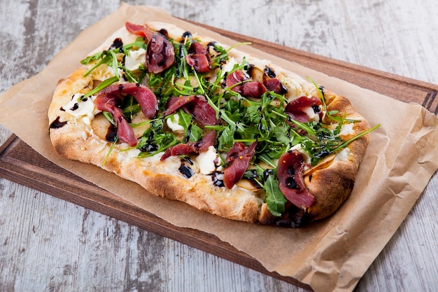 Pizza sur pâte moelleuse au jambon de Parme, poire et fromage blanc et sauce balsamique à la roquette