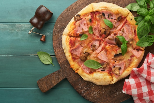 Pizza Pizza traditionnelle au bacon avec jambon, champignons, concombre et fromage marinés et ingrédients de cuisine tomates basilic sur fond de table en bois Cuisine traditionnelle italienne Vue de dessus Maquette