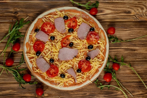 Pizza sur planche de bois, avec tomates et basilic, style italien sur une vieille table en bois, vue de dessus.