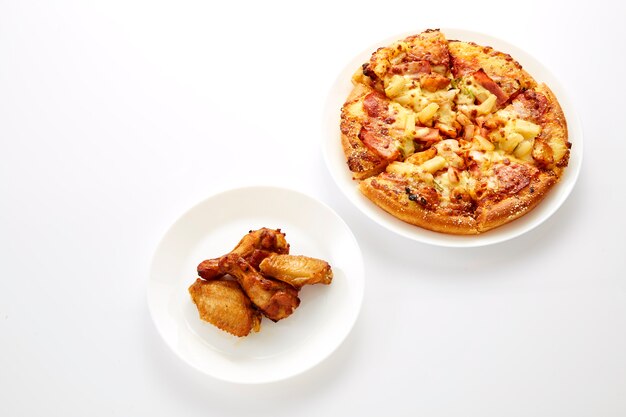 Pizza et poulets frits sont assiette blanche