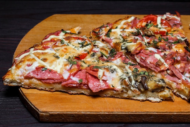 Pizza rustique italienne trois morceaux sur une table en bois foncée de plateau en bois