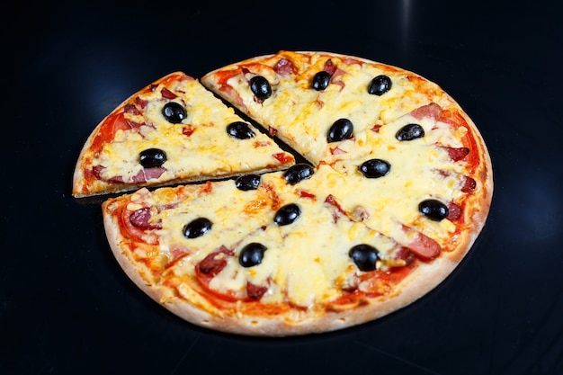 Pizza avec sauce tomate au fromage, olives, mozzarella fraîche, parmesan et basilic et viande sur fond sombre