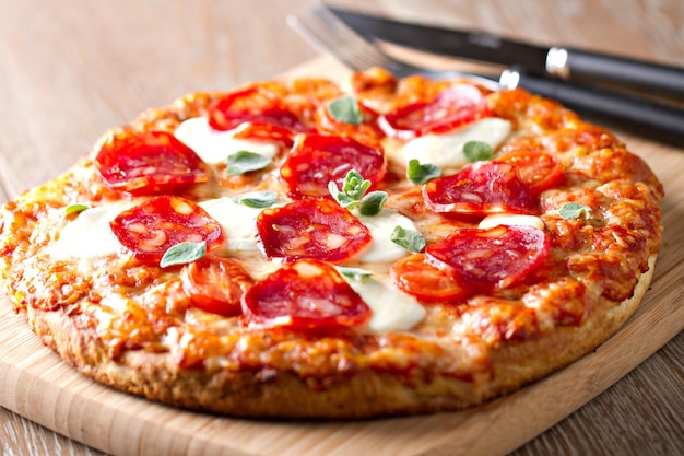 Pizza avec saucisse au pepperoni et fromage sur une planche en bois sur un fond en bois