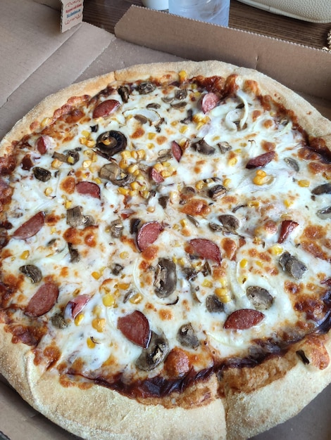 Pizza à la saucisse dans une boîte en carton