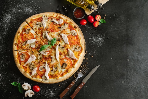 Pizza savoureuse avec de la viande de poulet sur fond noir