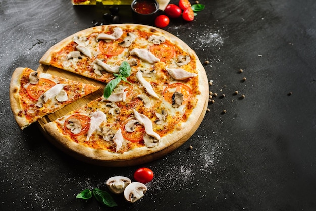 Pizza savoureuse avec de la viande de poulet sur fond noir