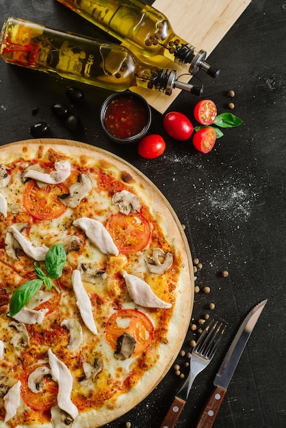 Pizza savoureuse avec de la viande de poulet sur fond noir