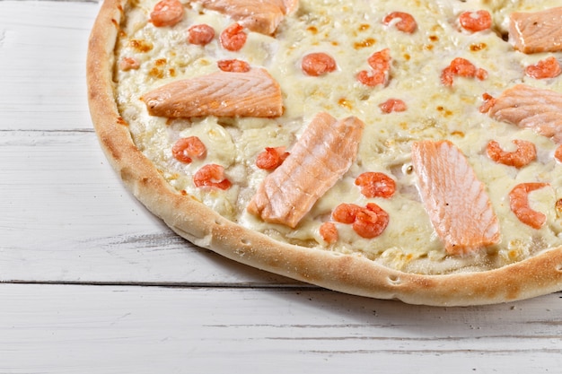 Photo pizza suprême au saumon et crevettes servie sur table en bois. pizza aux fruits de mer