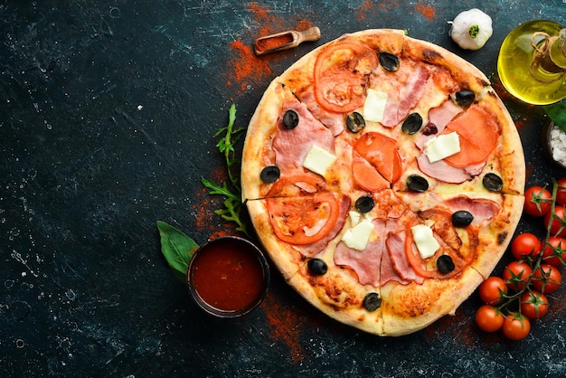 Pizza traditionnelle aux tomates bacon et fromage Sur fond de pierre noire Espace libre pour le texte