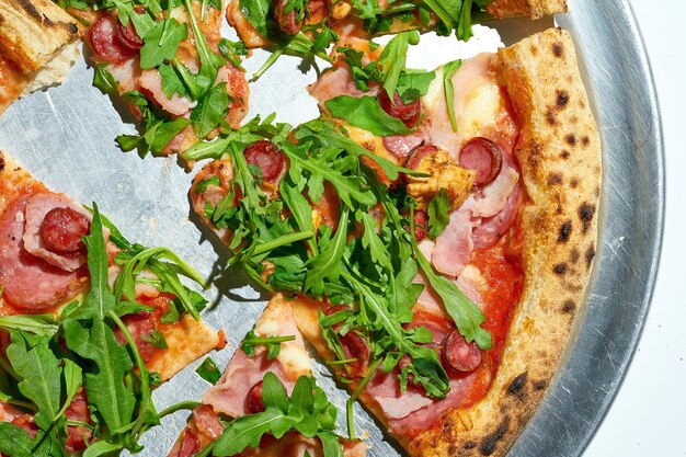 Pizza en tranches avec saucisse de salami et roquette isolé sur fond blanc