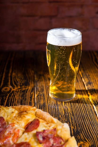 Pizza avec une variété de garnitures et de fromage sur une table en bois près d'un verre de bière