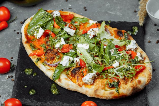 Pizza végétarienne aux tomates au fromage et aux légumes verts.