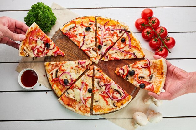 Pizza végétarienne fraîchement cuite au four avec tomates, champignons, poivrons rouges, oignons et mozzarella servis sur fond de bois avec des sauces et des herbes Concept de livraison de nourriture Menu du restaurant