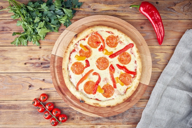 Photo pizza à la viande, légumes et champignons, fond en bois