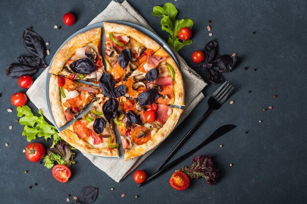 Pizza à la viande maison savoureuse avec tomates Pepperoni Bacon et basilic sur fond sombre