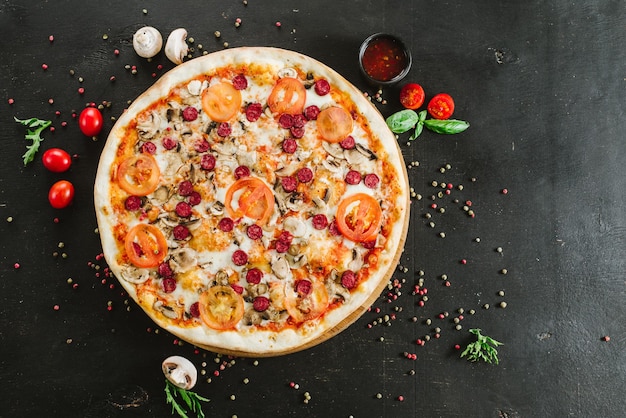 Pizza à la viande savoureuse avec divers ingrédients sur fond noir